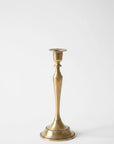 A single brass candlestick holder with a flared base and a slender, tapered stem, shown against a plain white background.