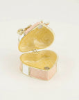 An open heart-shaped jewelry box with a gold-tone metal frame, featuring a light pink and white marbled inlay on the exterior and a matching marbled interior.