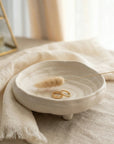 White ceramic dish with gold rings on a textured surface with soft lighting
