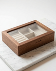 Wooden jewelry box with glass lid on a marble surface