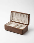 A rectangular wooden jewelry box with an open lid, featuring a dark brown wood exterior and a cream-colored interior with compartments and a ring roll.