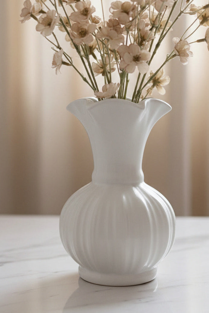 White vase with ribbed texture holding flowers on a light background