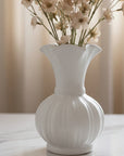 White vase with ribbed texture holding flowers on a light background