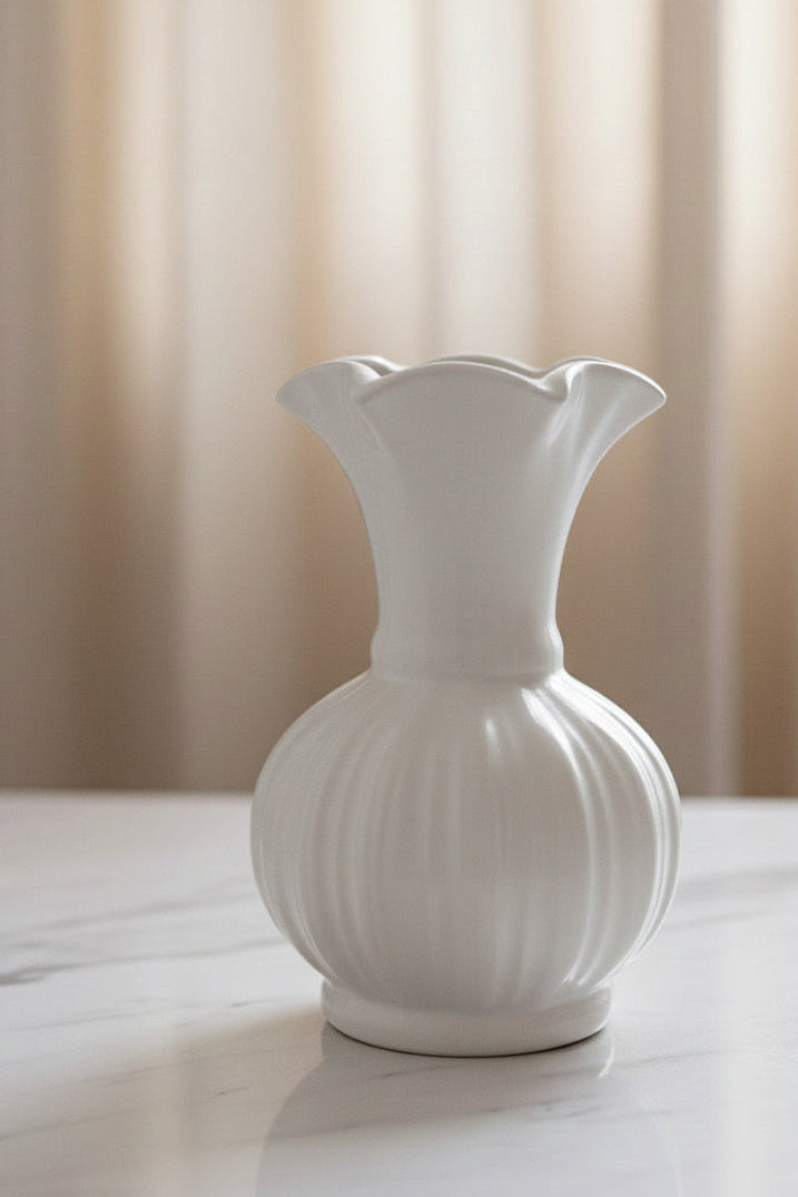 White ceramic vase on a light surface with a neutral background