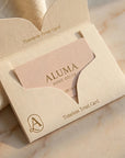 An open cream-colored gift card envelope with a pale blush pink card inside, featuring the brand name ALUMA HOME · DECOR and the text 'Timeless Treat Card' on a softly lit marble surface.