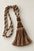 A decorative curtain tassel with twisted braided cords in brown, beige, and cream tones, photographed on a plain light background.