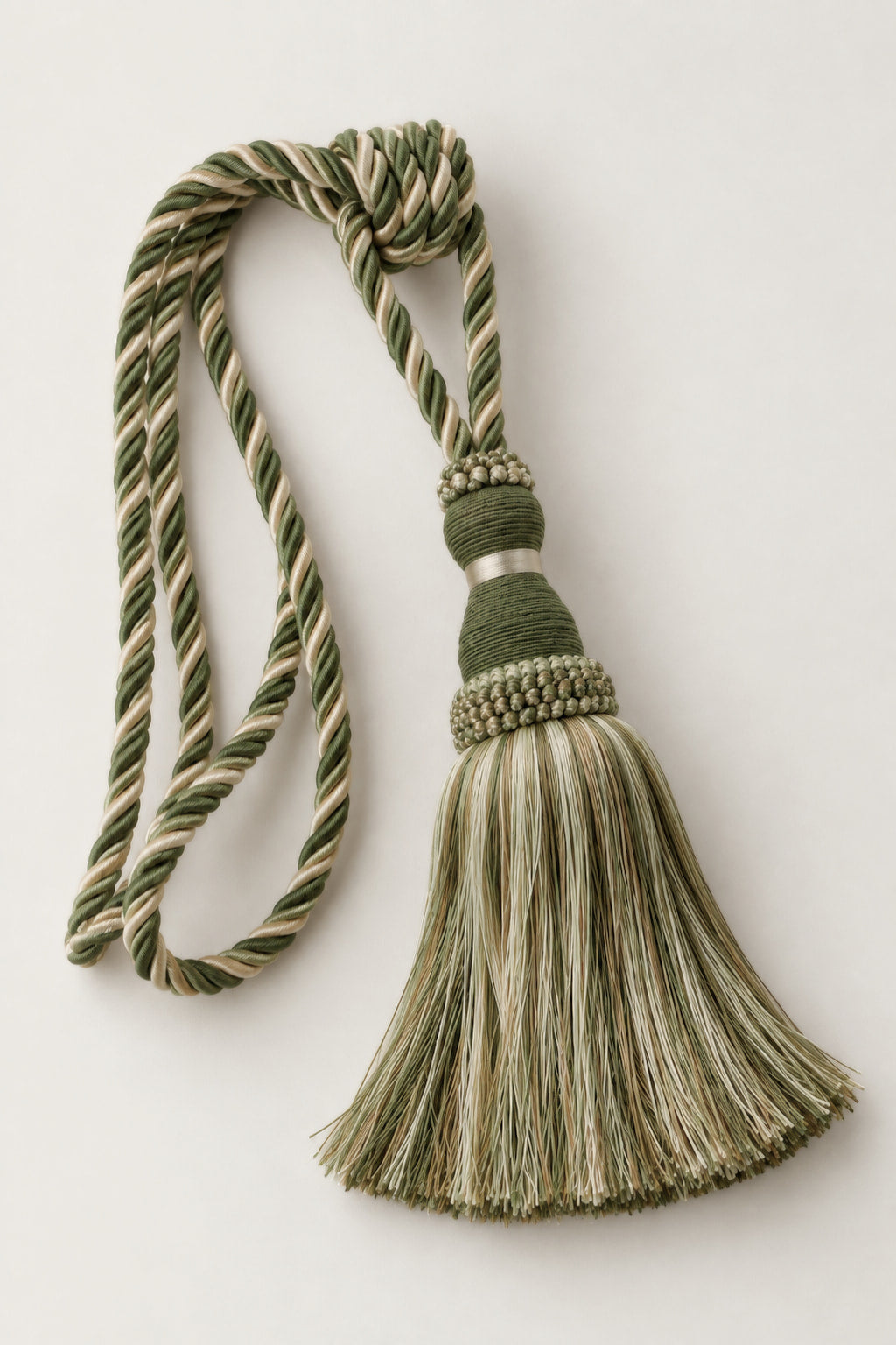 A decorative curtain tassel with a twisted rope cord in olive green and cream, a knotted top, and a fringed tassel, shown on a plain light background.