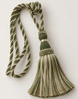 A decorative curtain tassel with a twisted rope cord in olive green and cream, a knotted top, and a fringed tassel, shown on a plain light background.