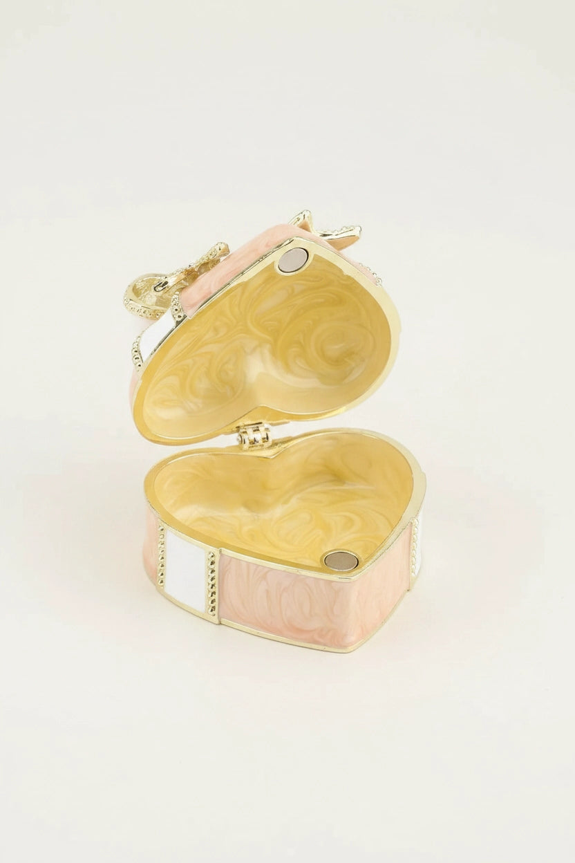 An open heart-shaped jewelry box with a gold-tone metal frame, featuring a light pink and white marbled inlay on the exterior and a matching marbled interior.