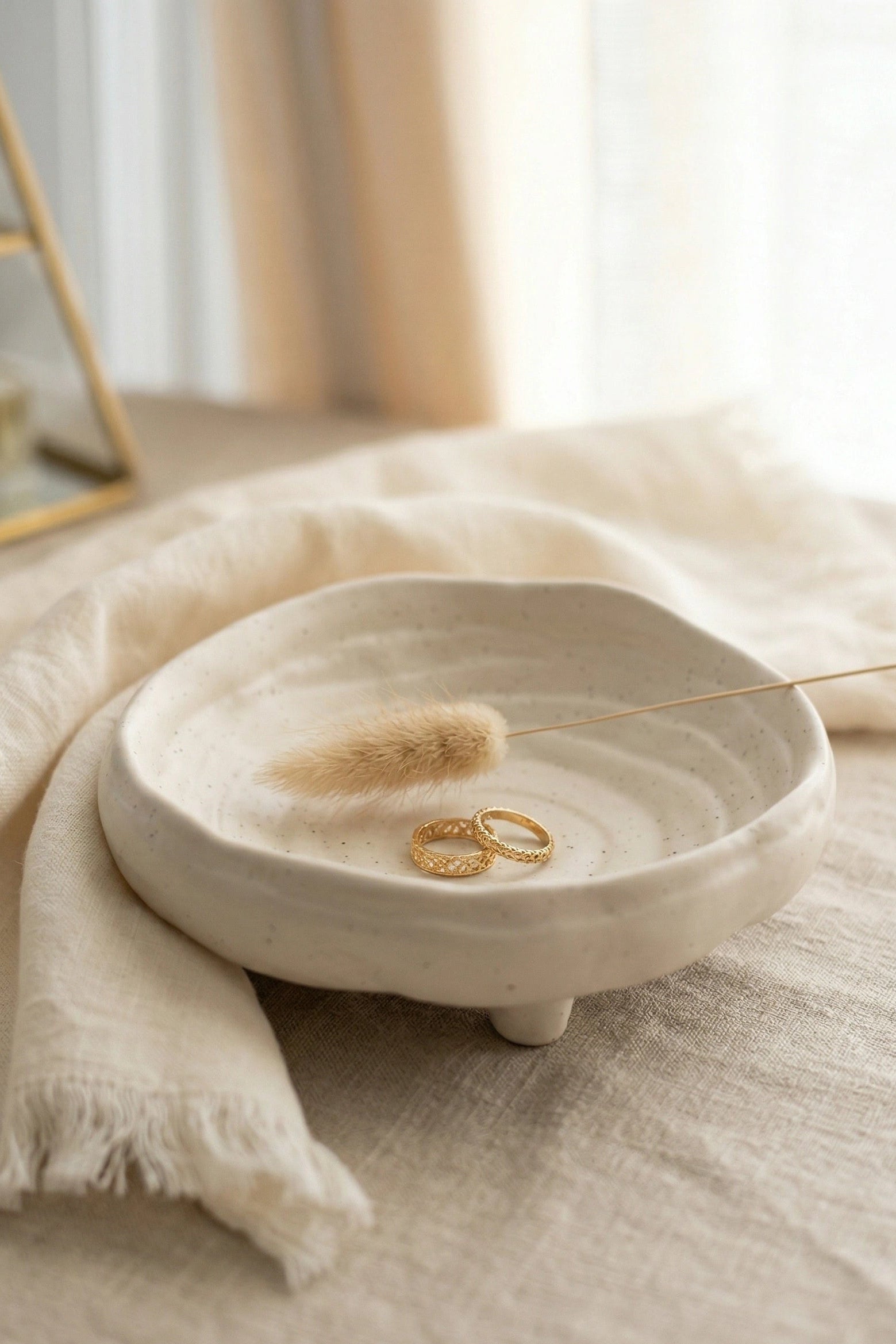 White ceramic dish with gold rings on a textured surface with soft lighting