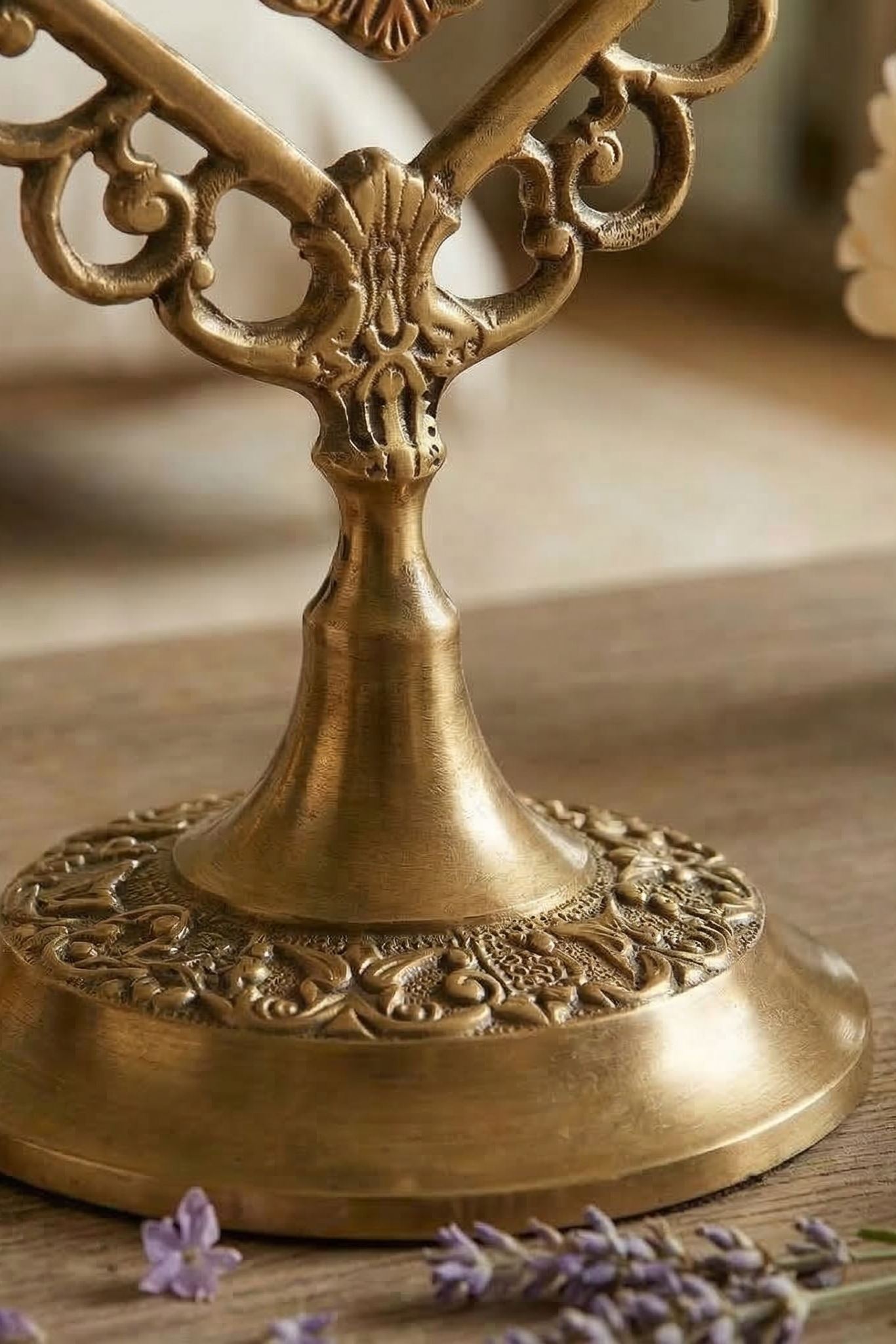 close up of  brass mirror  with intricate designs on a wooden surface with lavender flowers.