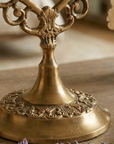 close up of  brass mirror  with intricate designs on a wooden surface with lavender flowers.