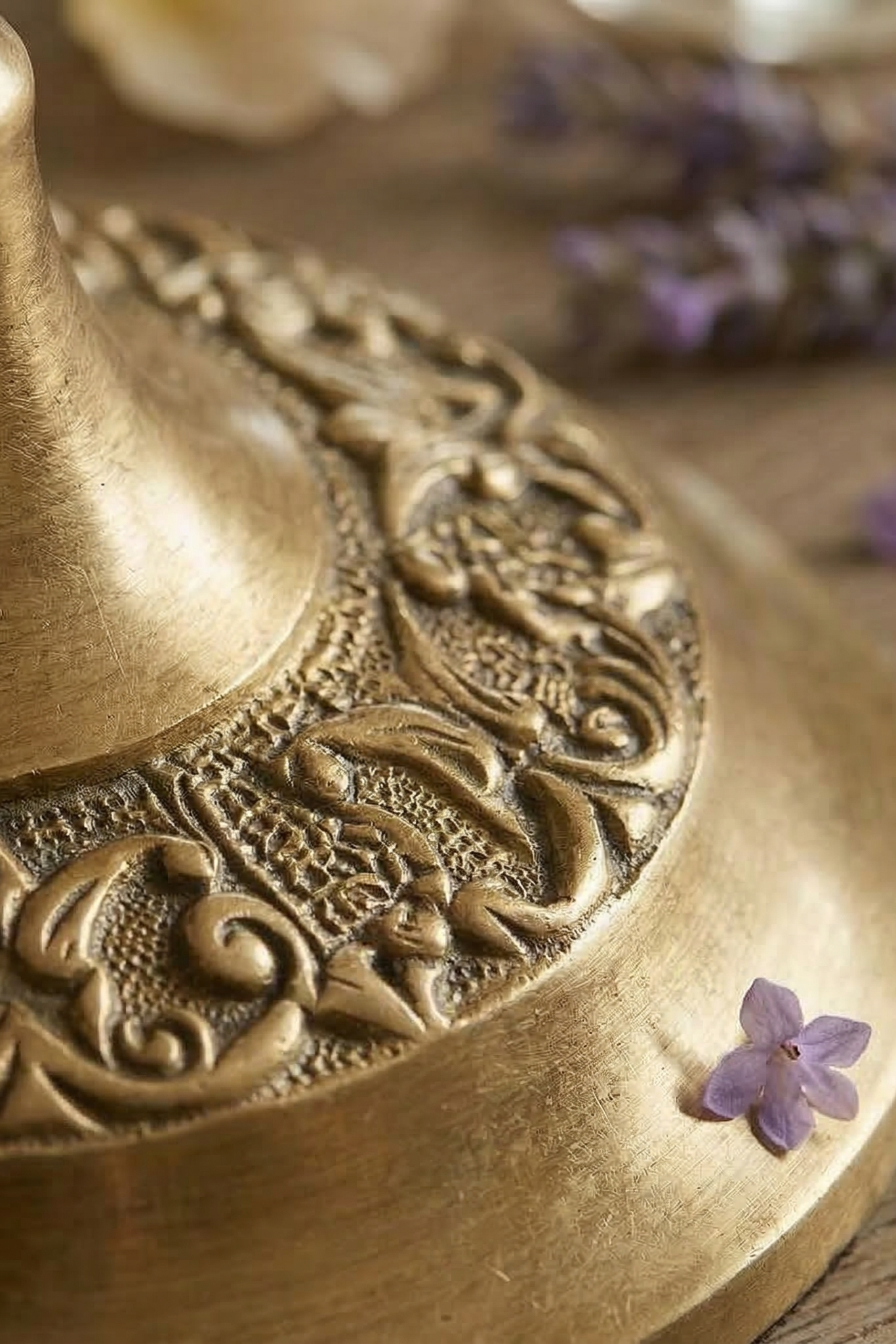 Close-up of a brass ornate mirror  with a purple flower on a wooden surface