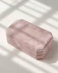 A dusty pink velvet octagonal jewelry box with a textured velvet finish, photographed on a light beige surface with soft window shadow overlays.