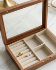 Wooden jewelry box with glass top on a marble surface