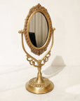 Decorative brass vanity mirror on a white background