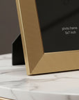 Gold photo frame on a marble surface with text indicating size.