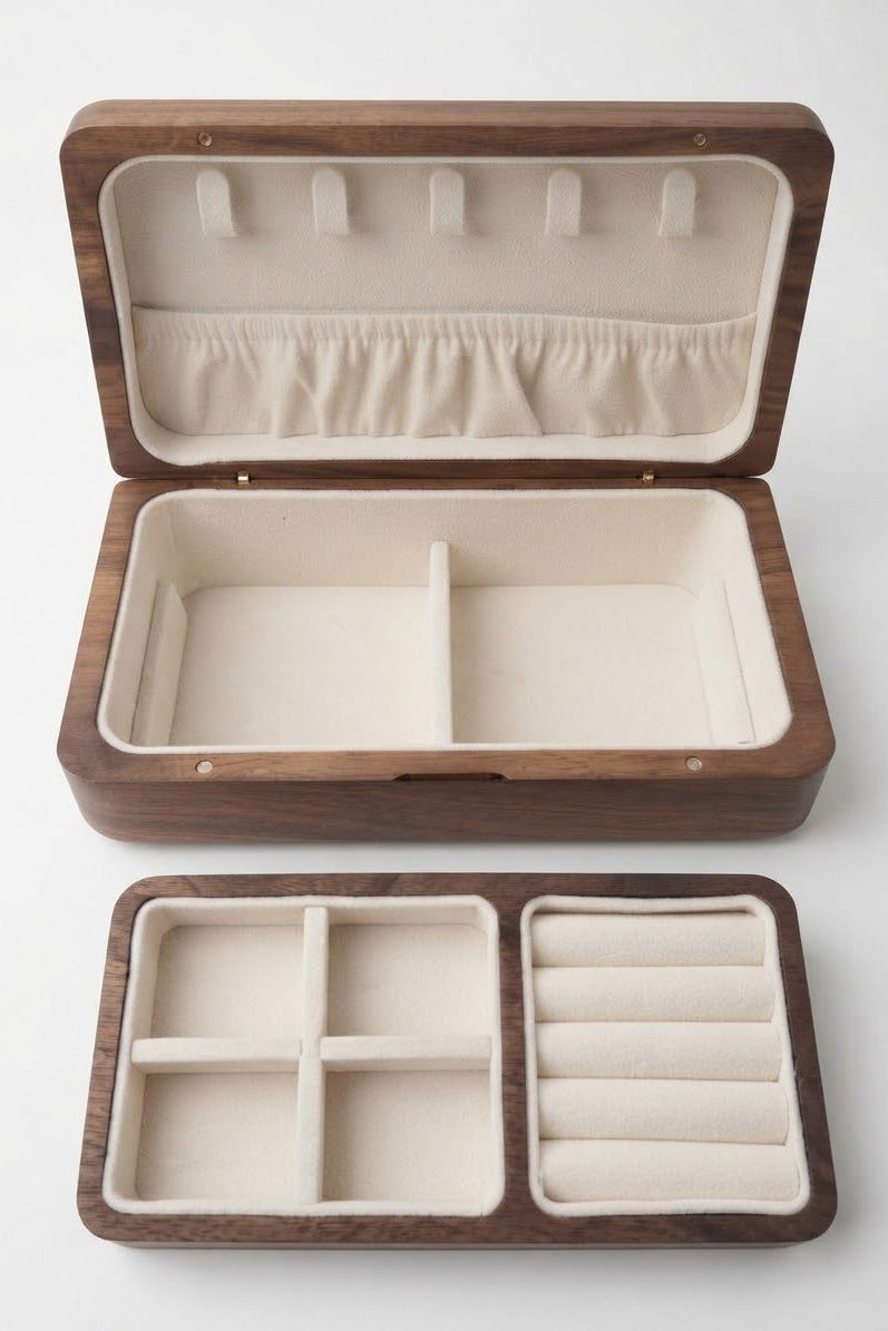An open rectangular wooden jewelry box with cream-colored velvet interior compartments, shown above its matching closed lid on a light gray background.