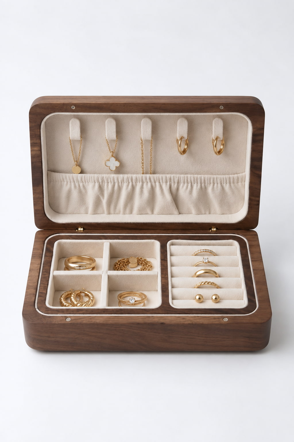 An open wooden jewelry box with a dark brown wood grain exterior and cream-colored velvet interior, displaying various gold rings, necklaces, and earrings in organized compartments.
