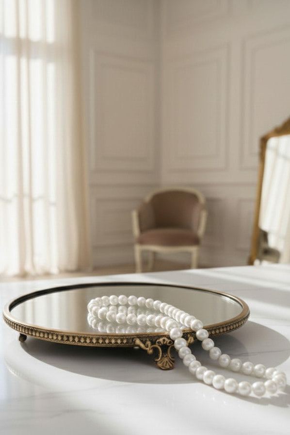 Pearl necklace on a decorative brass tray with a blurred room background