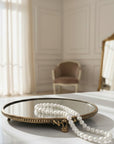 Pearl necklace on a decorative brass tray with a blurred room background