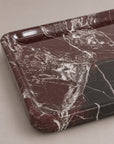 A rectangular marble tray with rounded corners, featuring a dark reddish-brown and black marble pattern with white veining, photographed on a neutral beige background.