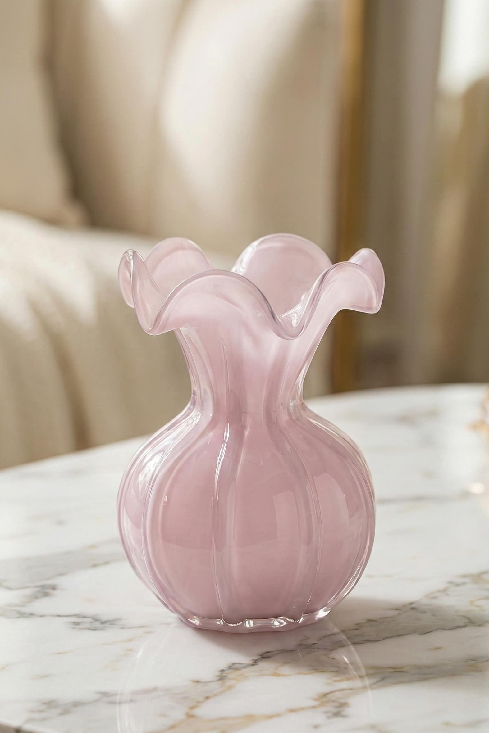 Pink glass vase on a marble surface with a blurred background
