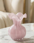 Pink glass vase on a marble surface with a blurred background