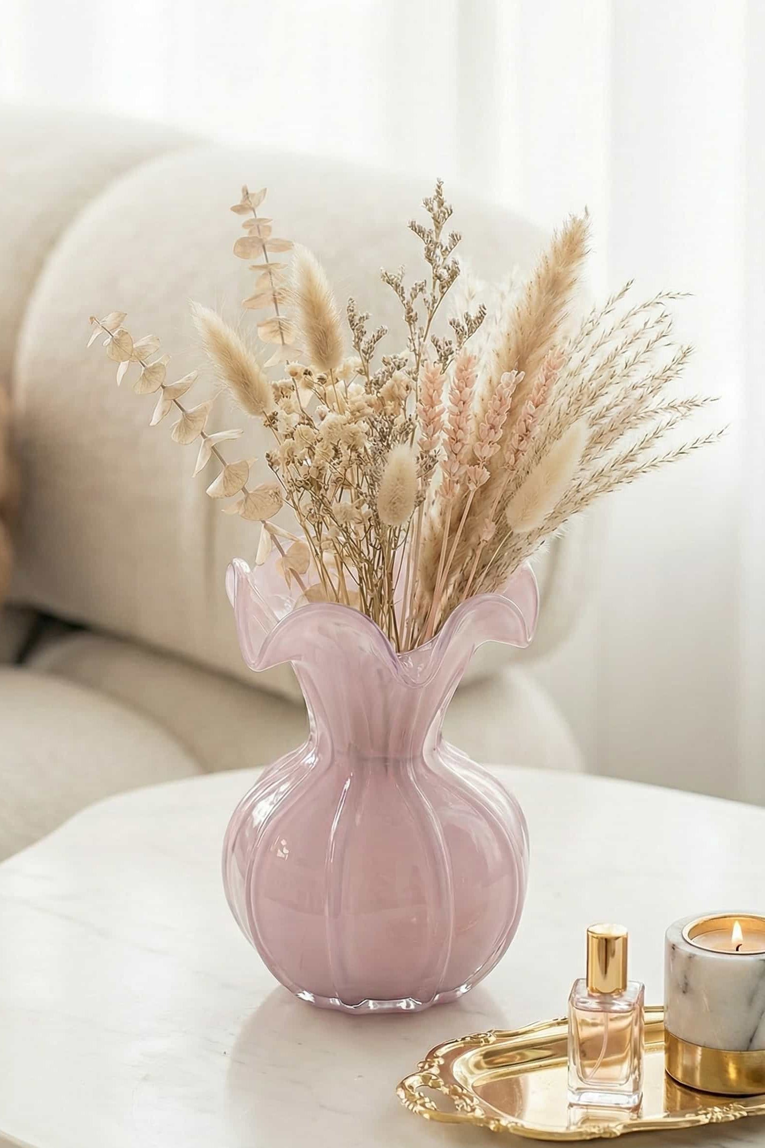Pink vase with dried flowers on a white surface with a blurred background