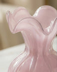 Pink glass vase with wavy design on a blurred background